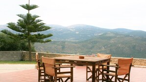 A wooden table and chairs on a patio with a mountain view. - Lagoon View Apartments - Adults Only (Kefalonia)