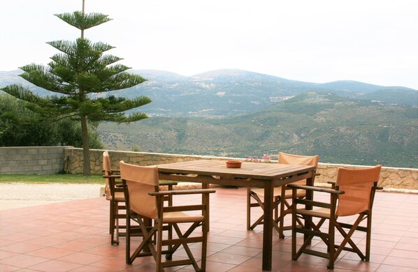 A wooden table and chairs on a patio with a mountain view.