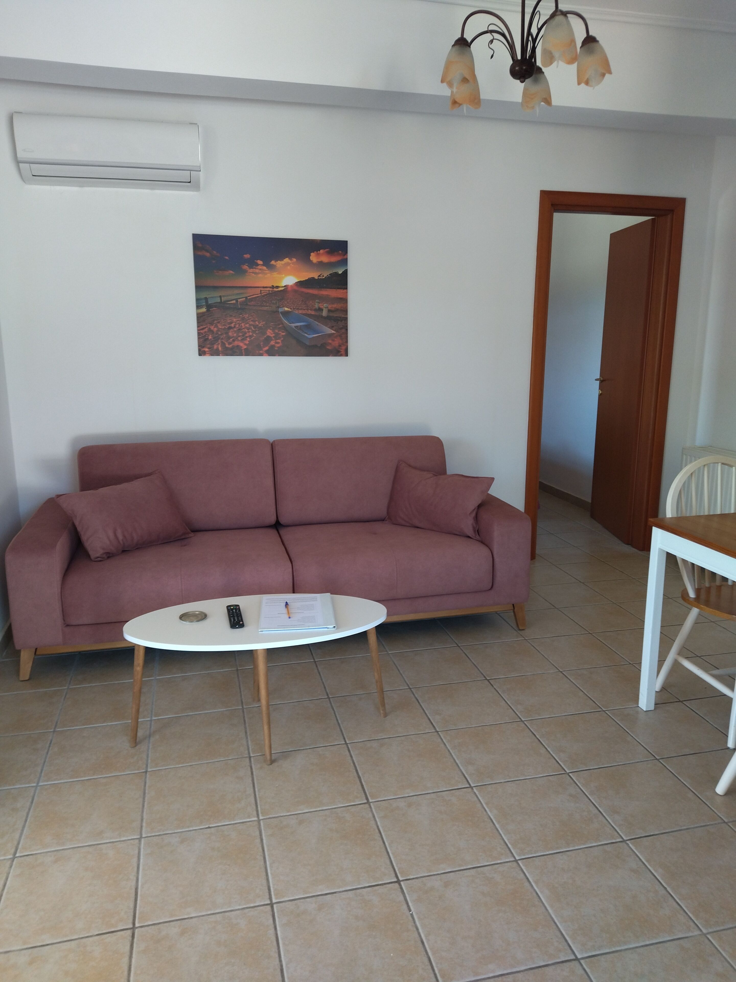 Una sala de estar con un sofá, una mesita redonda y un cuadro en la pared.