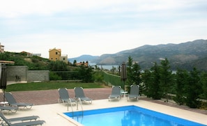 A swimming pool with lounge chairs and a view of mountains and a lake. - Lagoon View Apartments - Adults Only (Kefalonia)