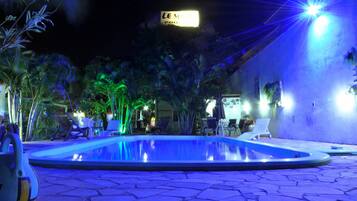 Una piscina al aire libre, sillones reclinables de piscina