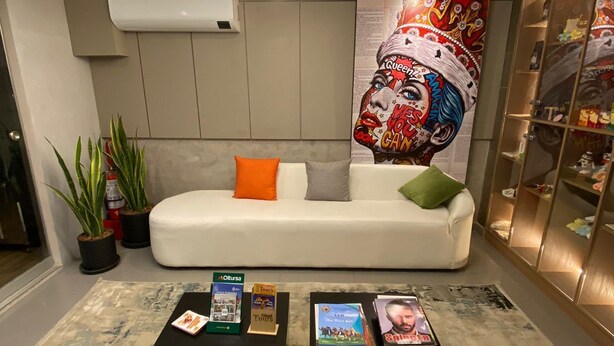A modern living room with a white sofa, two black coffee tables, and a large decorative painting. - YOURS HOTEL LIFESTYLE (Chiclayo)