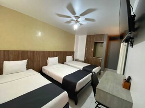 A hotel room with two beds, a ceiling fan, a TV, and a small table with a remote control. - YOURS HOTEL LIFESTYLE (Chiclayo)