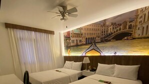 A hotel room with two single beds, a desk, a chair, a ceiling fan, and a large window with a cityscape view. - YOURS HOTEL LIFESTYLE (Chiclayo)