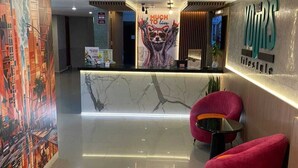 A modern reception area with a marble counter, red chairs, and a cityscape mural. - YOURS HOTEL LIFESTYLE (Chiclayo)