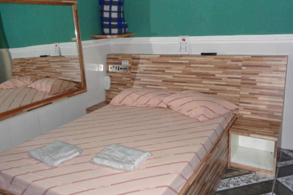 Ein Schlafzimmer mit einem hölzernen Kopfende, einem Bett mit gestreifter Bettwäsche, einem Nachttisch und einem Spiegel.