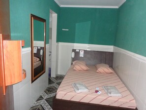 A small, narrow room with a bed, a mirror, and a telephone. - Hotel Flor do Gomide (São Paulo)