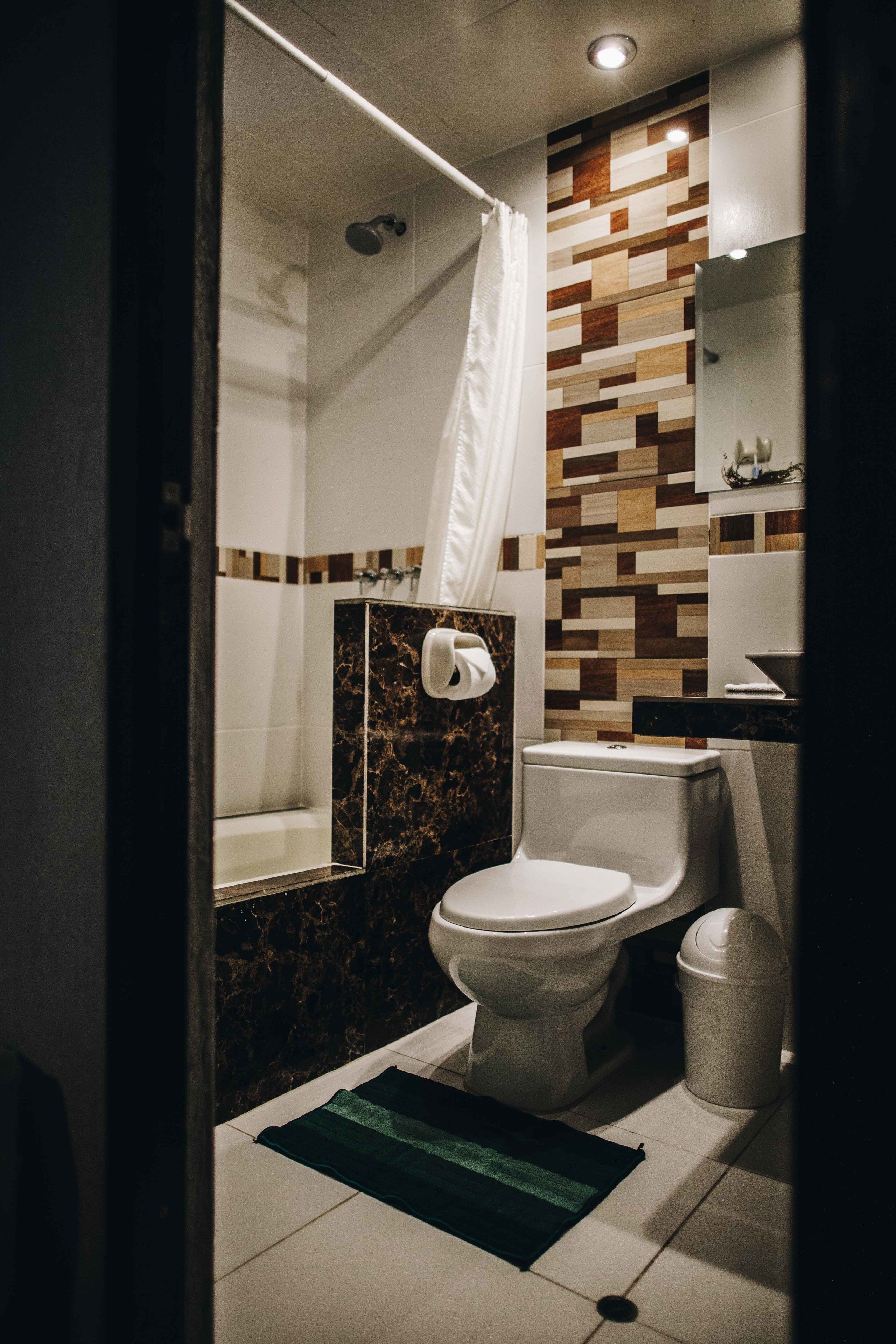 Un baño con inodoro, ducha y espejo.