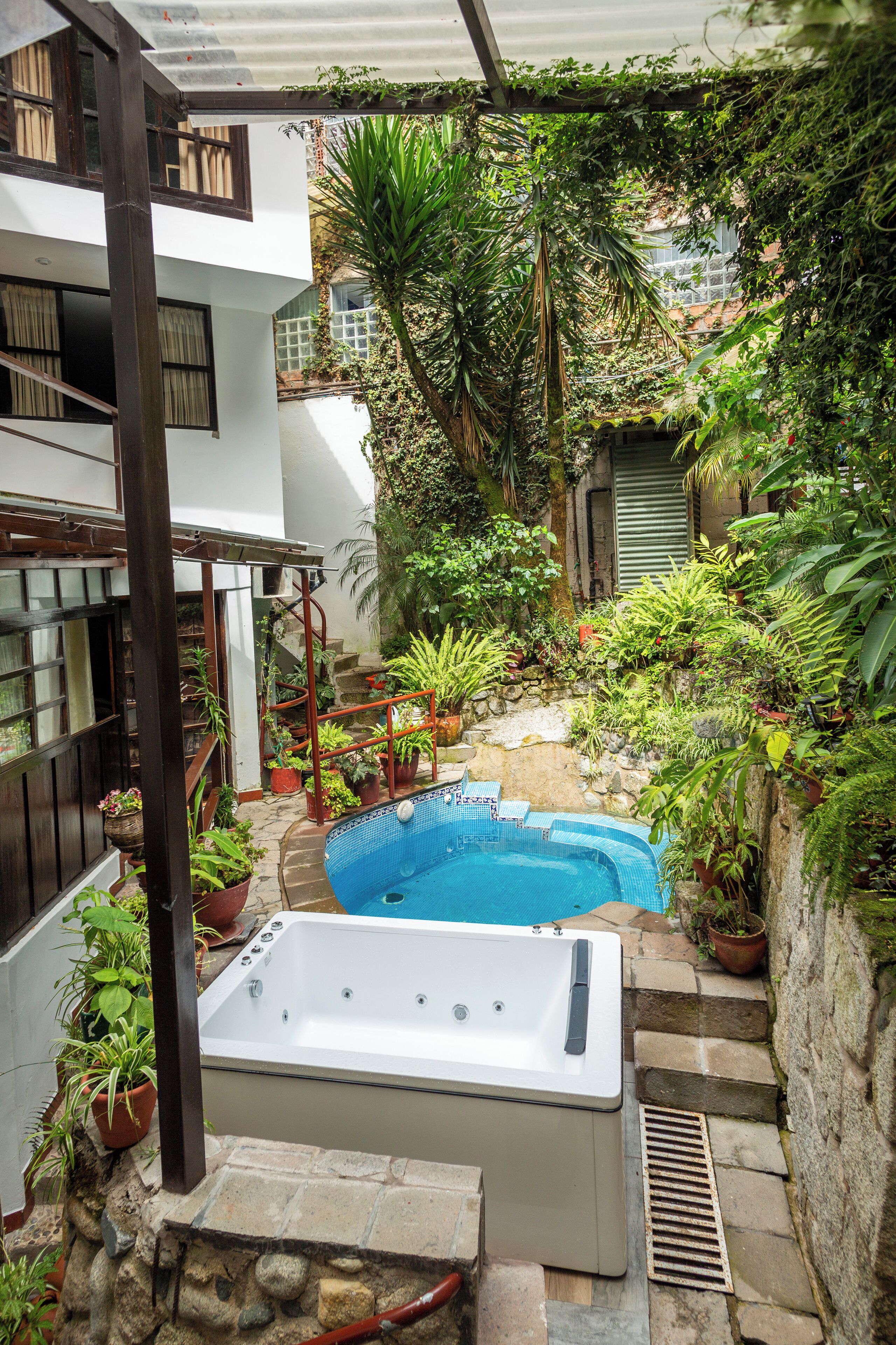 A rooftop garden with a hot tub, potted plants, and a stone staircase.