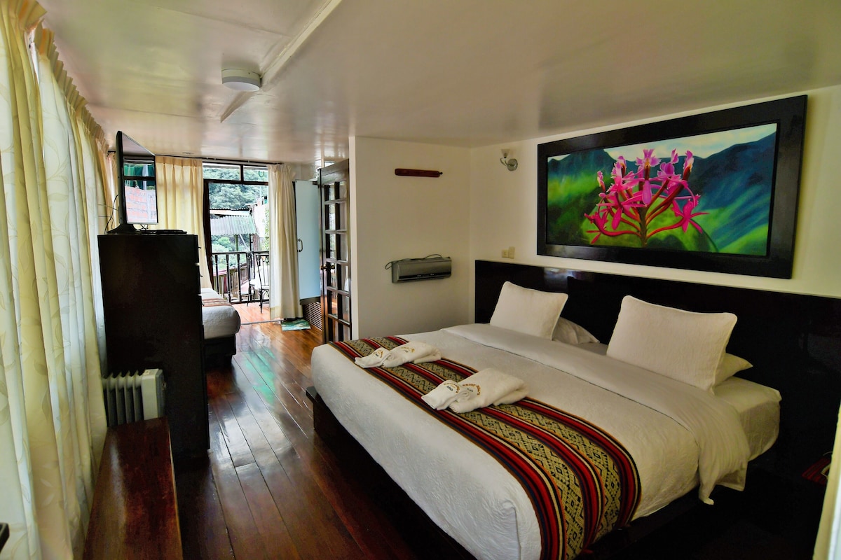 Une chambre d’hôtel avec un grand lit, une télévision et un tableau représentant des fleurs accroché au mur.