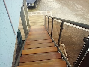 A wooden staircase with metal railings leading to an outdoor area.