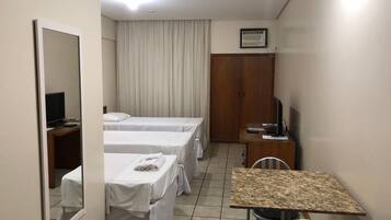A hotel room with two beds, a small table, a TV, and a wardrobe.