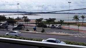 A view of a parking lot with several cars, a pedestrian walkway, and a body of water in the background. - Hotel Sol da Praia (Vitoria)