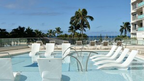 A pool area with lounge chairs and a view of the ocean. - Ilikai Lite (Honolulu)