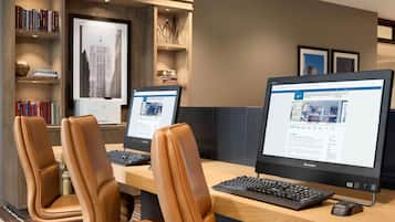 A modern office setup with two monitors, a keyboard, and leather chairs.