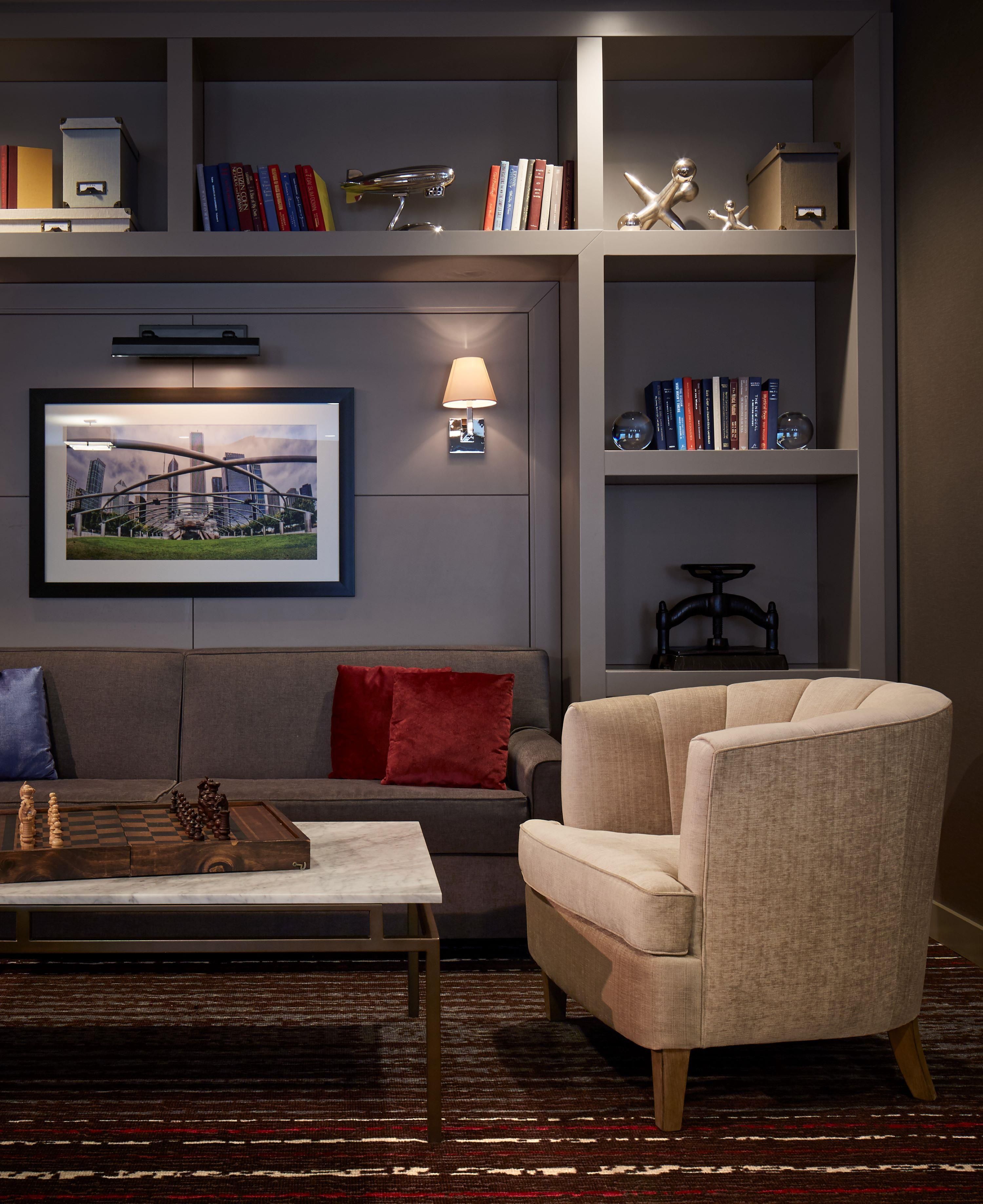 A modern living room with a sofa, armchair, coffee table, and a bookshelf with books and decorative items.