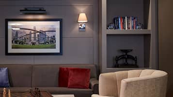 A modern living room with a sofa, armchair, coffee table, and a bookshelf with books and decorative items.