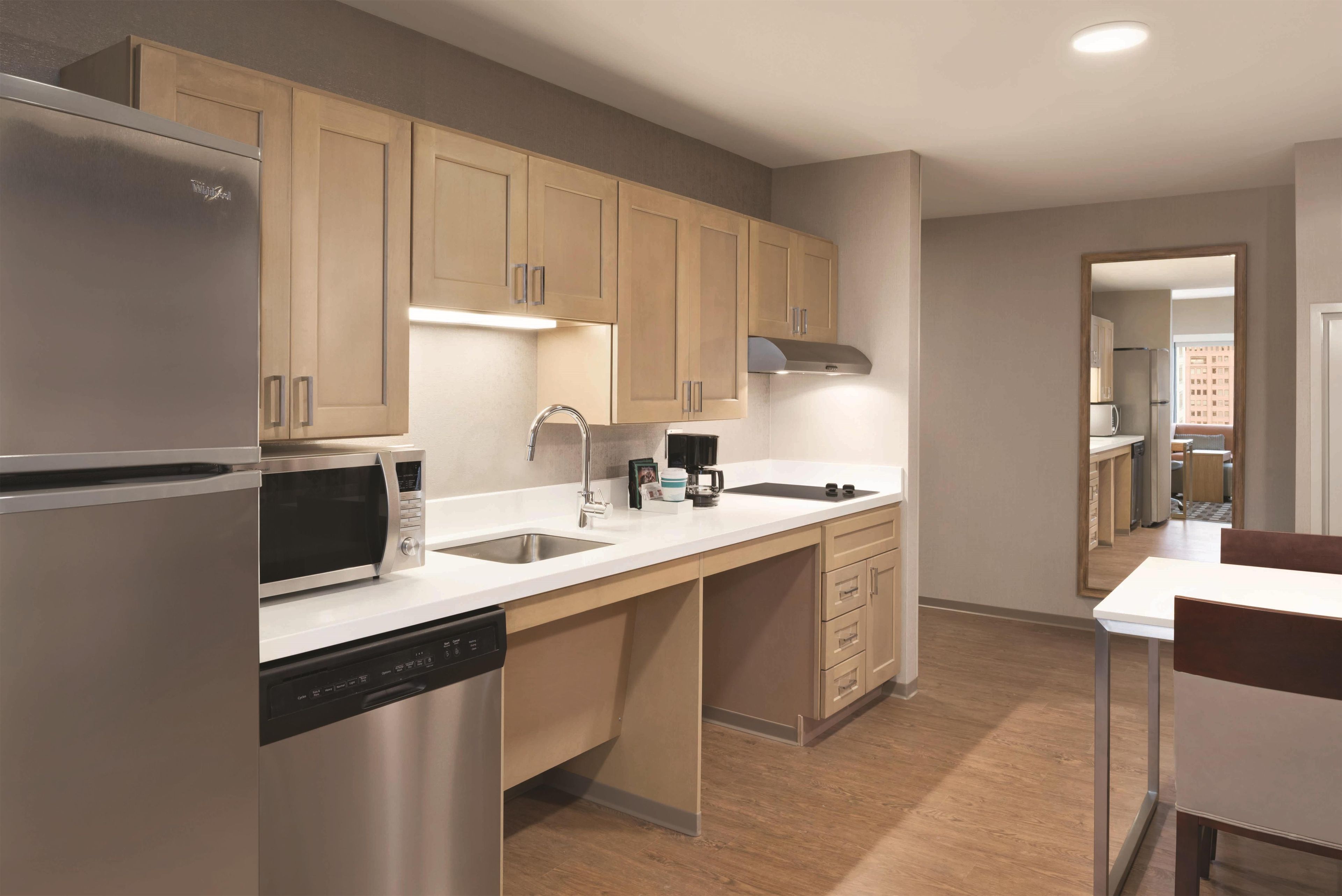 A modern kitchen with a built-in dishwasher, a microwave, a coffee maker, and a stainless steel refrigerator.
