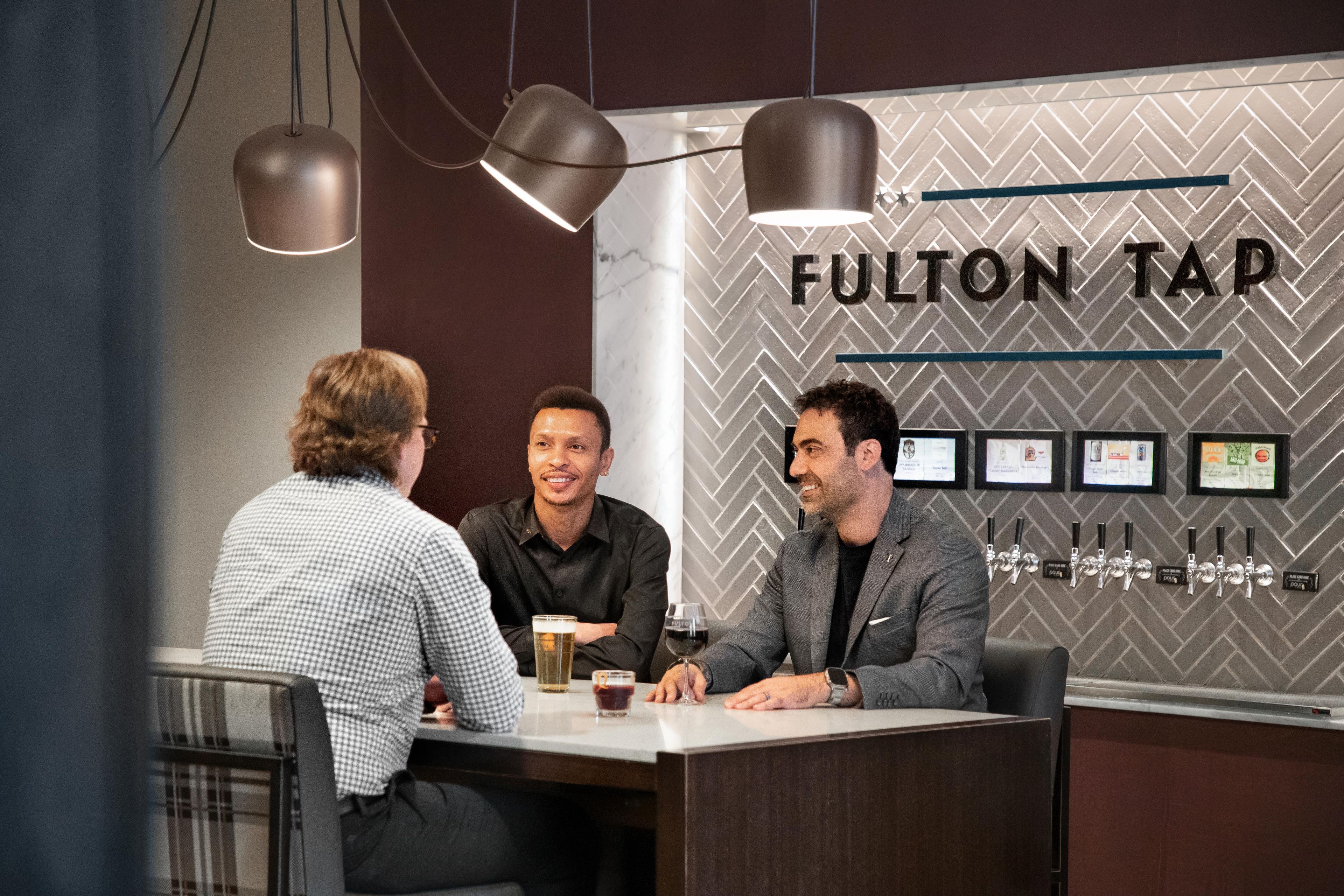 A bar area with a sign reading 'FULTON TAP' and beer taps.