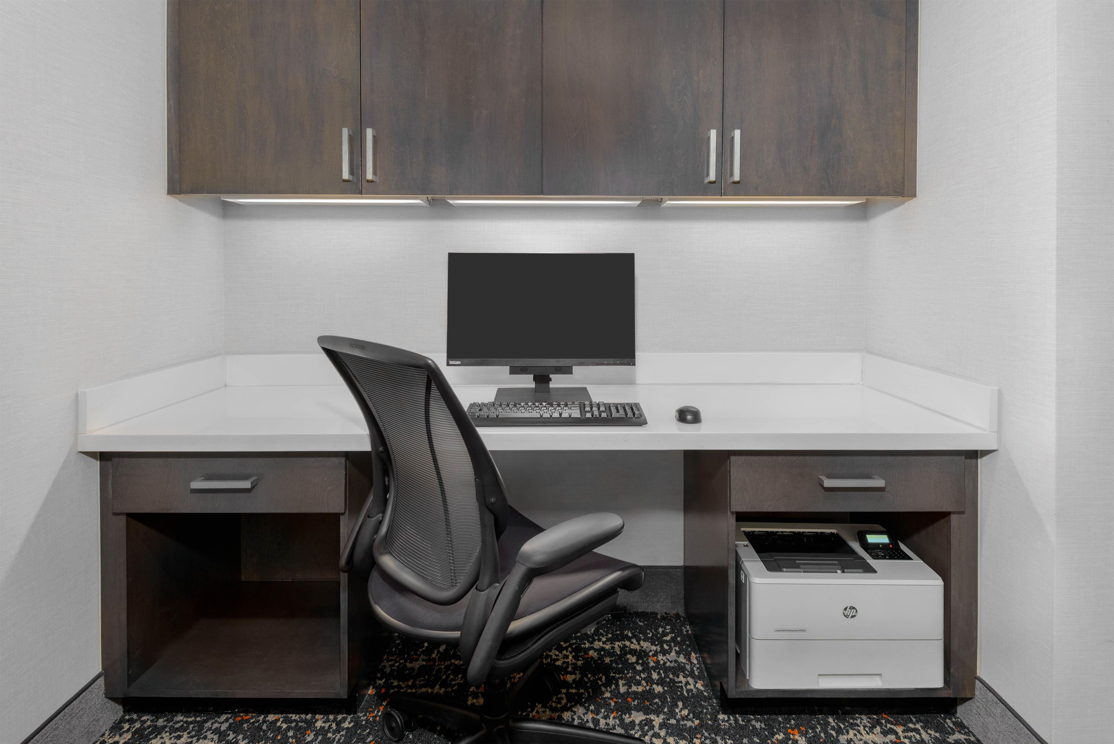 A modern office desk with a computer, chair, and printer.