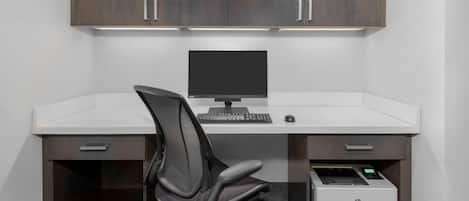 Un escritorio moderno con computadora, silla e impresora.