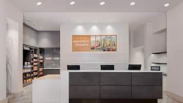 Ein Empfangsschalter mit einem 'Welcome to Hampton' Schild, einem Stadtbildgemälde und einer 'Hilton Honors' Plakette.