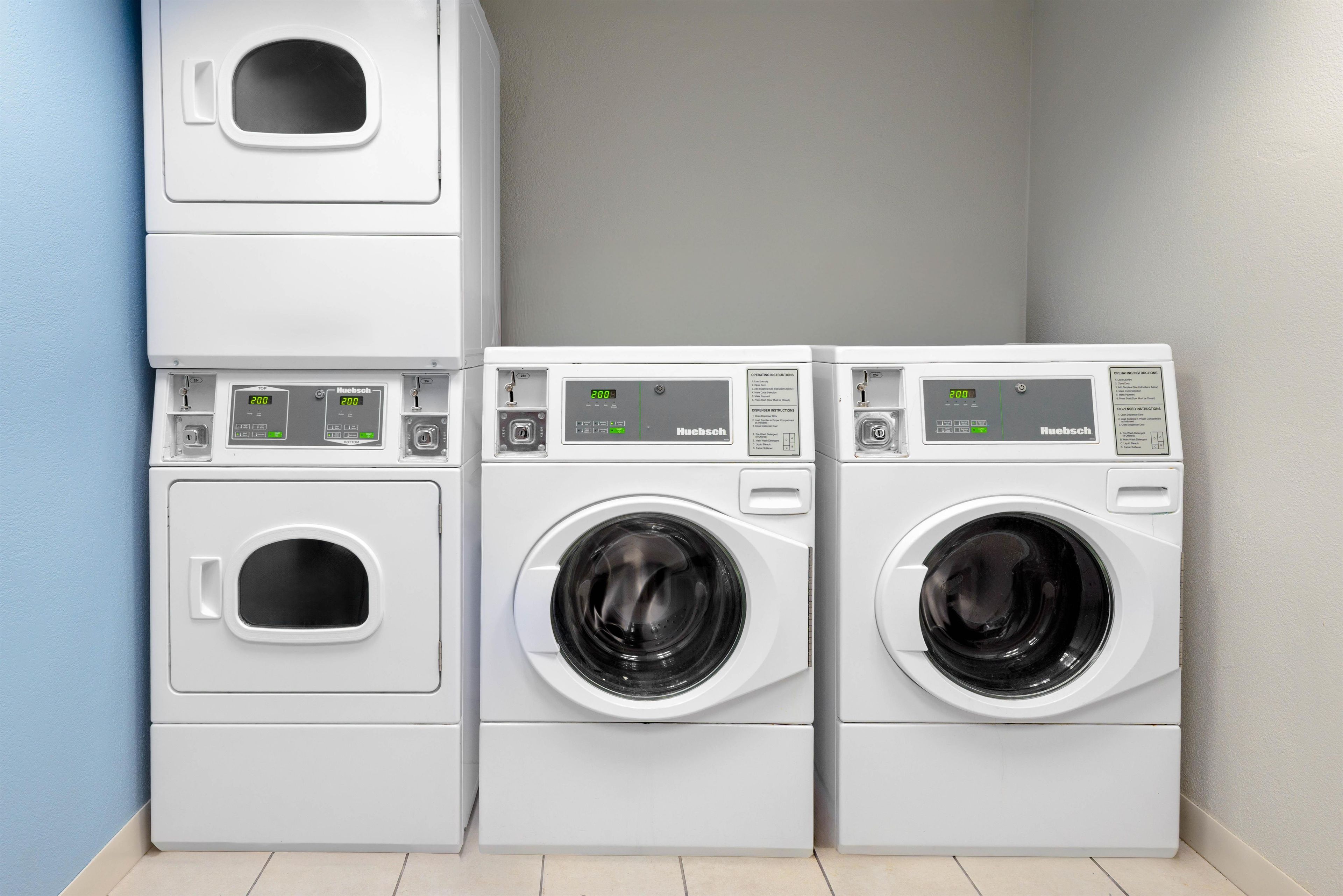 A laundry room with three stacked washing machines and a dryer.