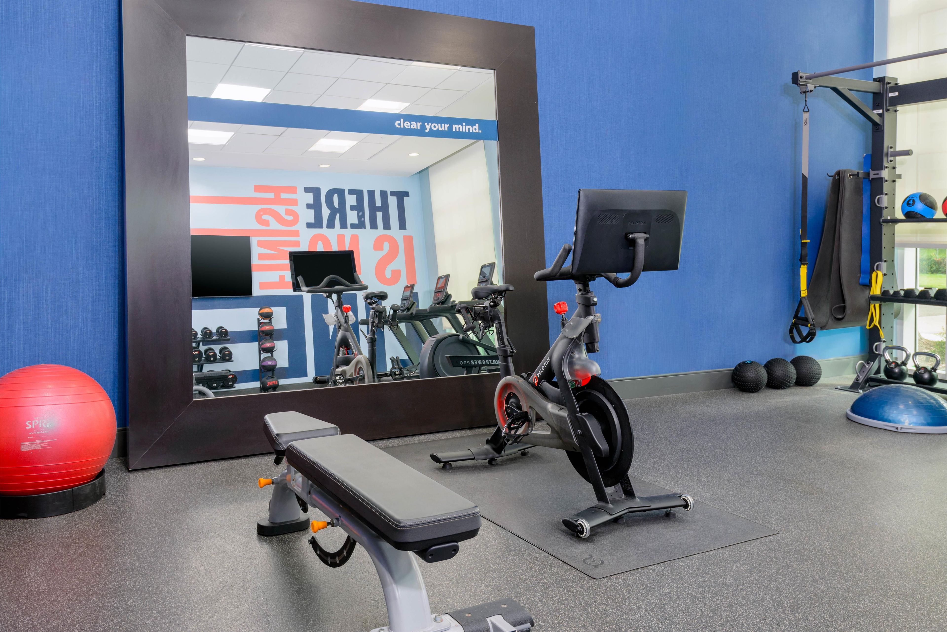 A gym with exercise equipment, a bench, and a wall with motivational text.