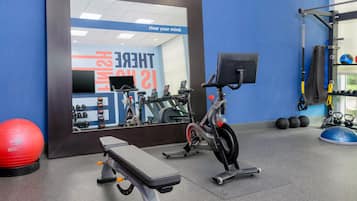 Un gimnasio con equipo de ejercicio, una banca y una pared con mensajes motivacionales.