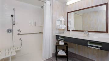 Un baño moderno con ducha, tocador con espejo y barra para toallas.
