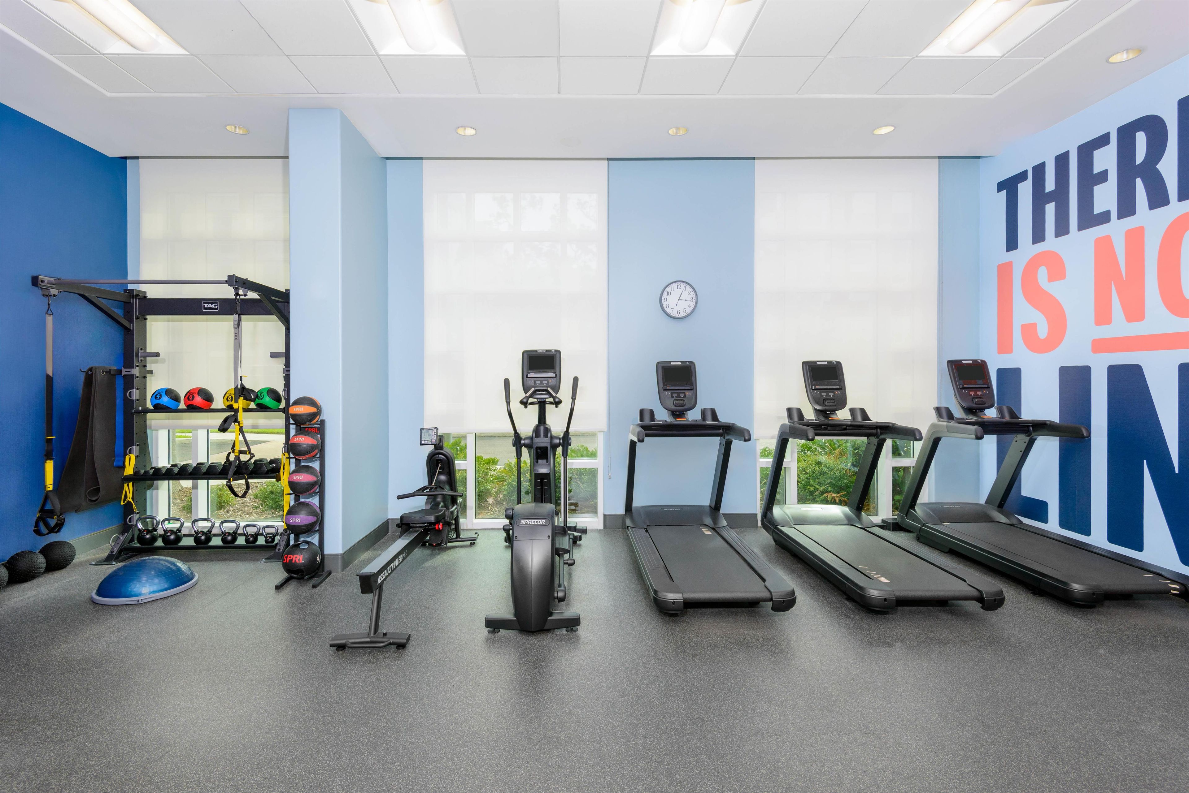 Un gimnasio con cintas de correr, una banca para pesas y diverso equipo de ejercicio.