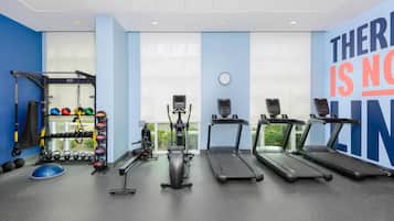 Un gimnasio con cintas de correr, una banca para pesas y diverso equipo de ejercicio.