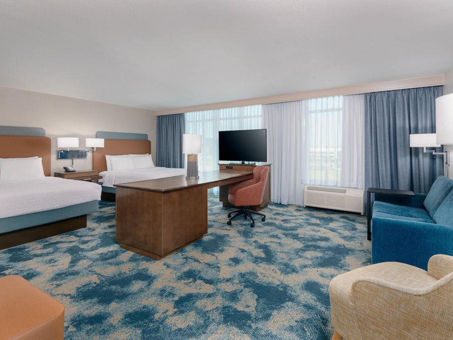 Een hotelkamer met twee bedden, een bureau, een televisie, een stoel en een bank.