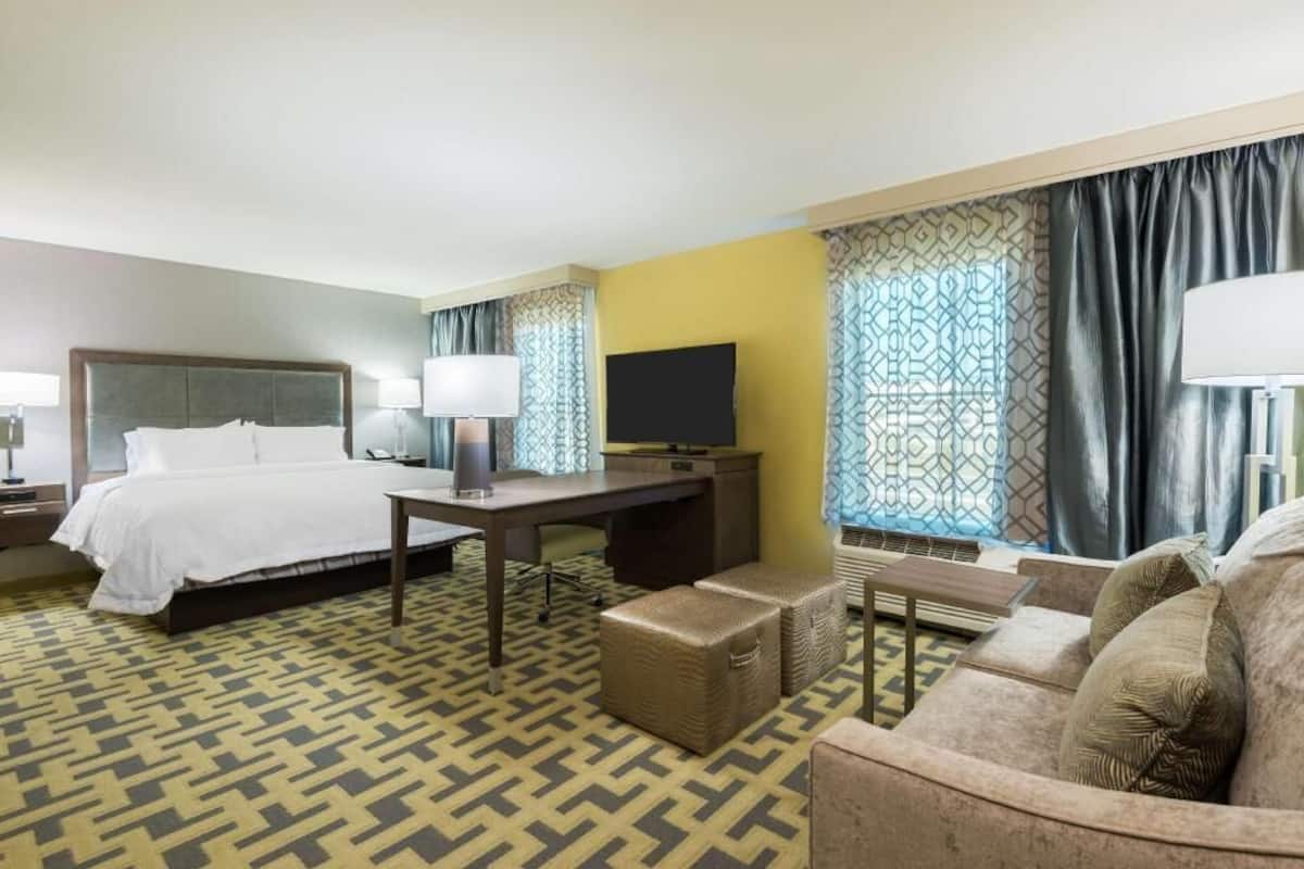 Une chambre d’hôtel équipée d’un lit, d’un bureau, d’une télévision et d’un canapé.