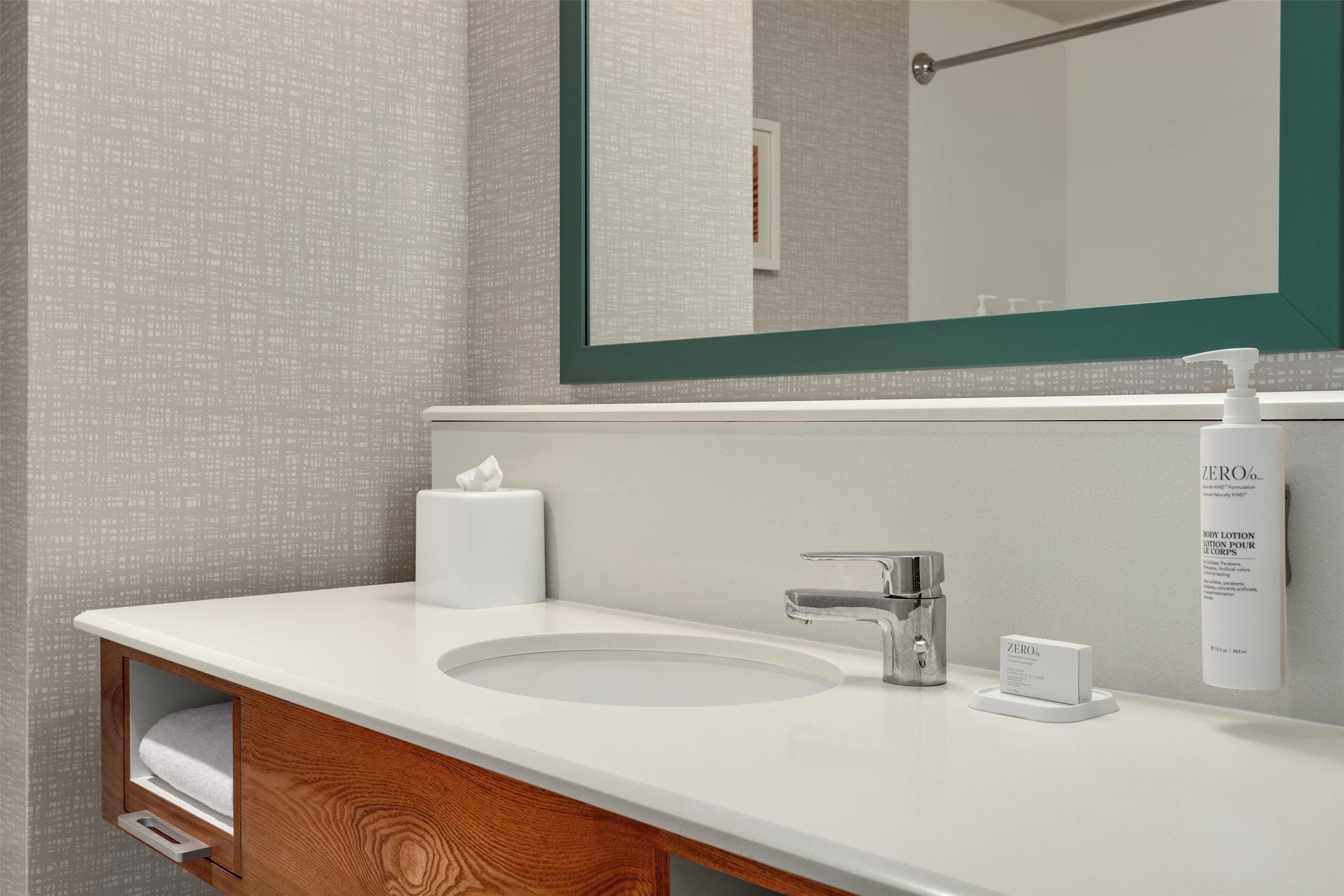 Une salle de bain avec un lavabo blanc, un miroir et un meuble-lavabo en bois.