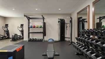 Ein Fitnessraum mit Trainingsgeräten, Gewichtsständern und einer Bank.
