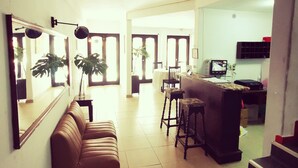 A spacious living area with a sofa, a dining table, and a kitchen area with a bar. - Costanera Hostel Asuncion (Asunción)