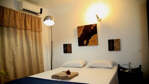 A hotel room with a bed, a bedside table, a lamp, and artwork on the wall. - Costanera Hostel Asuncion (Asunción)
