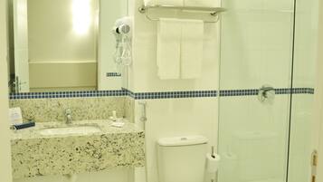 Baño con lavamanos, inodoro y cabina de ducha de vidrio.