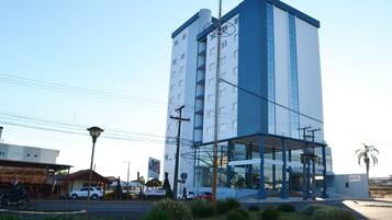 Un hotel moderno con una fachada destacada en azul y blanco, un acceso cubierto y una señal que indica que es un hotel.