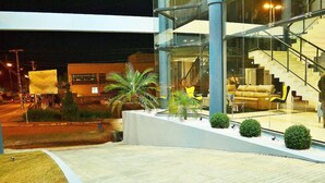 A modern building with a glass facade, a staircase leading to an upper level, and a landscaped area with small trees and shrubs. - Villa Premium Hotel (Erechim)