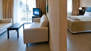 A hotel room with a sofa, a bed, a TV, and a balcony with curtains. - Alamos del Mar (Valeria del Mar)