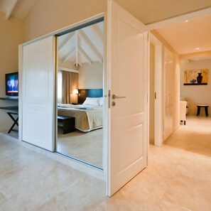 A hotel room with a sliding glass door leading to a bed, a desk with a television, and a bathroom visible through an open door. - Alamos del Mar (Valeria del Mar)