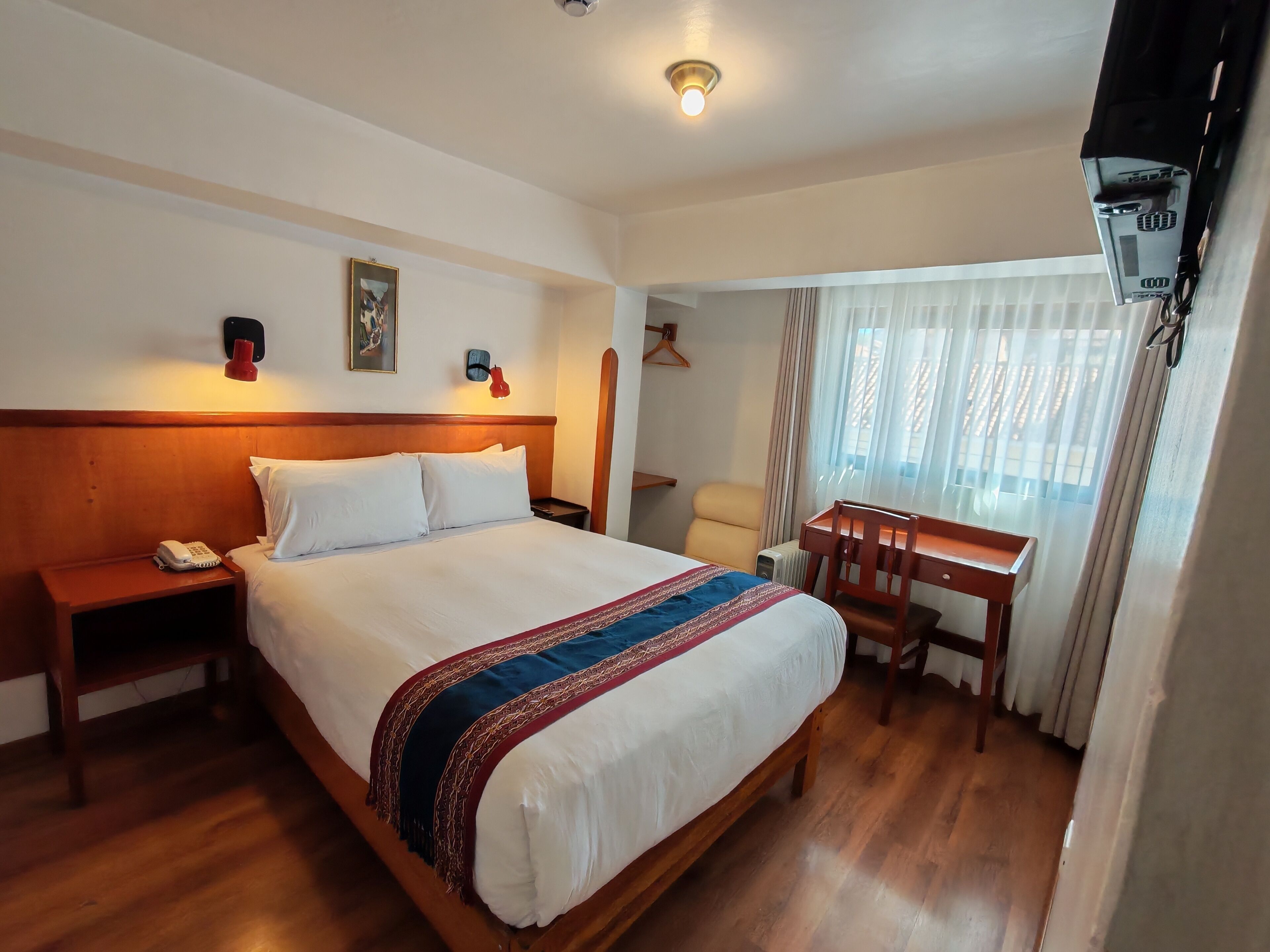 Una habitación de hotel con una cama de madera, un escritorio y una silla.