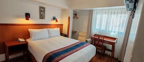 Una habitación de hotel con una cama de madera, un escritorio y una silla.
