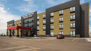 A modern hotel with a red awning, labeled "Encore Suites Service Place." It features a multi-story building with a parking lot in front.