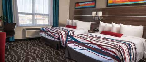 A hotel room with two beds, a desk, and a chair. There are two paintings on the wall and a window with curtains.