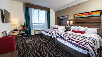 Habitación de hotel con dos camas, un escritorio, una silla, un televisor y una ventana con cortinas.