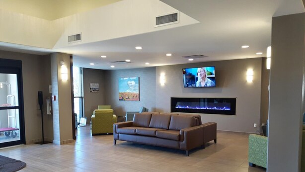 A modern lobby with a brown leather sofa, a television mounted on the wall, and a reception desk.
