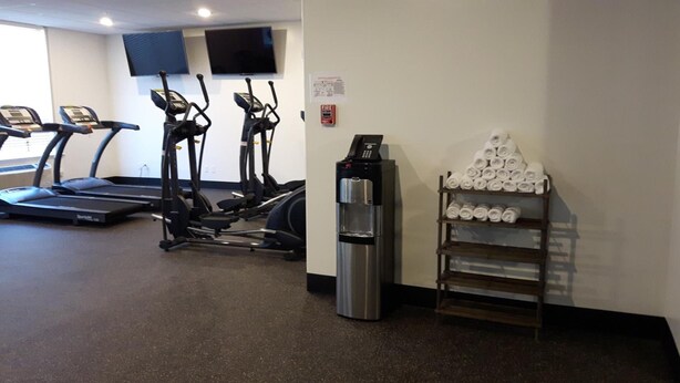A gym with treadmills, elliptical machines, and a water dispenser. - Encore Suites by Service Plus Inns (Grande Prairie)